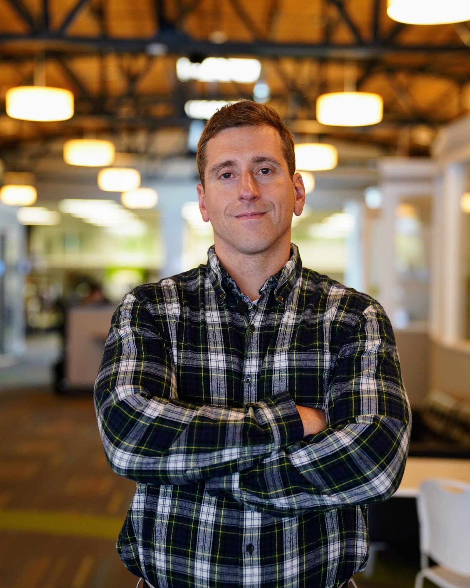 Michael Cox, arms folded, standing in an open office.